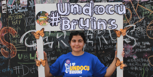 A student posing in a large paper Instagram frame